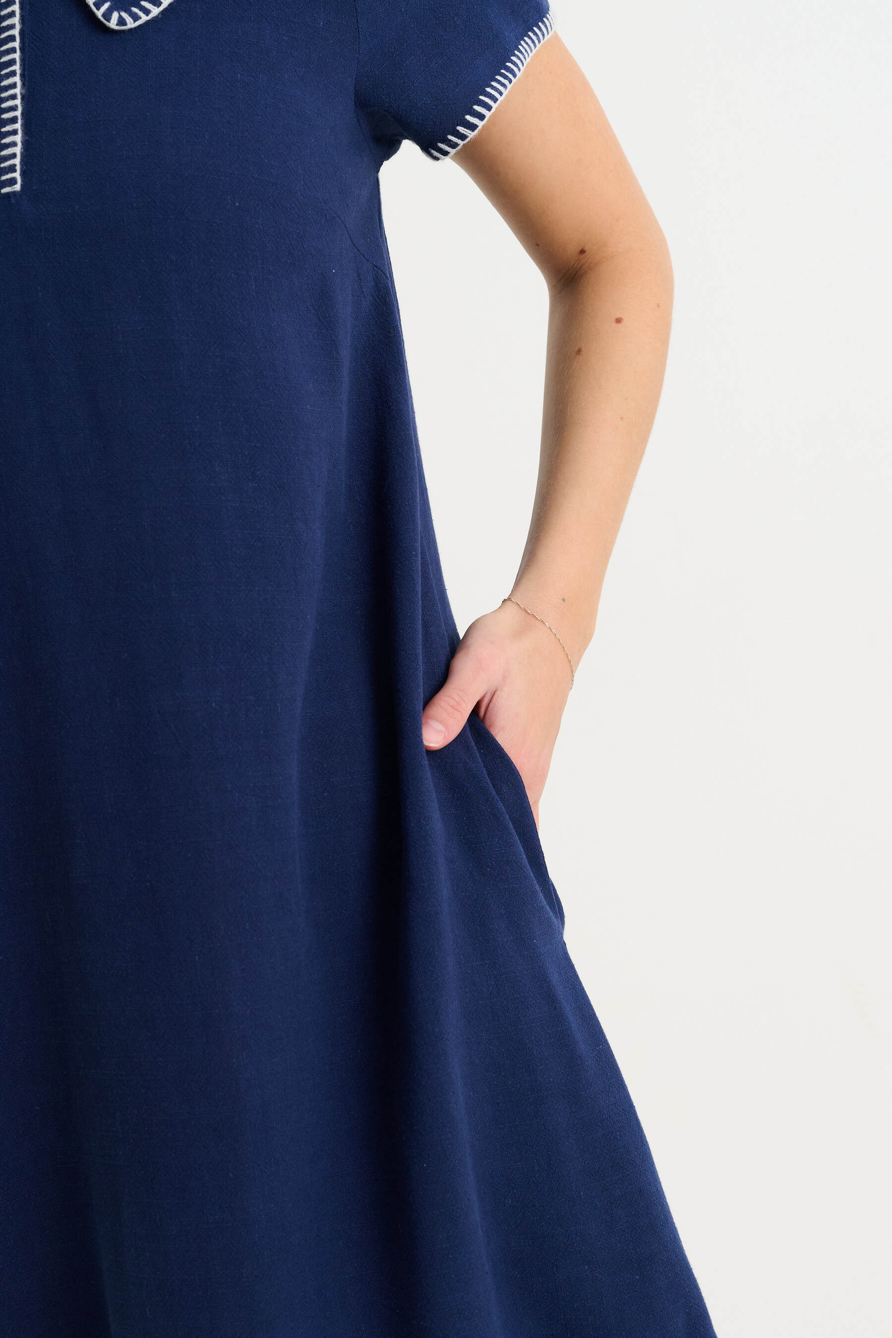 Navy blue dress with white trim on a plain background