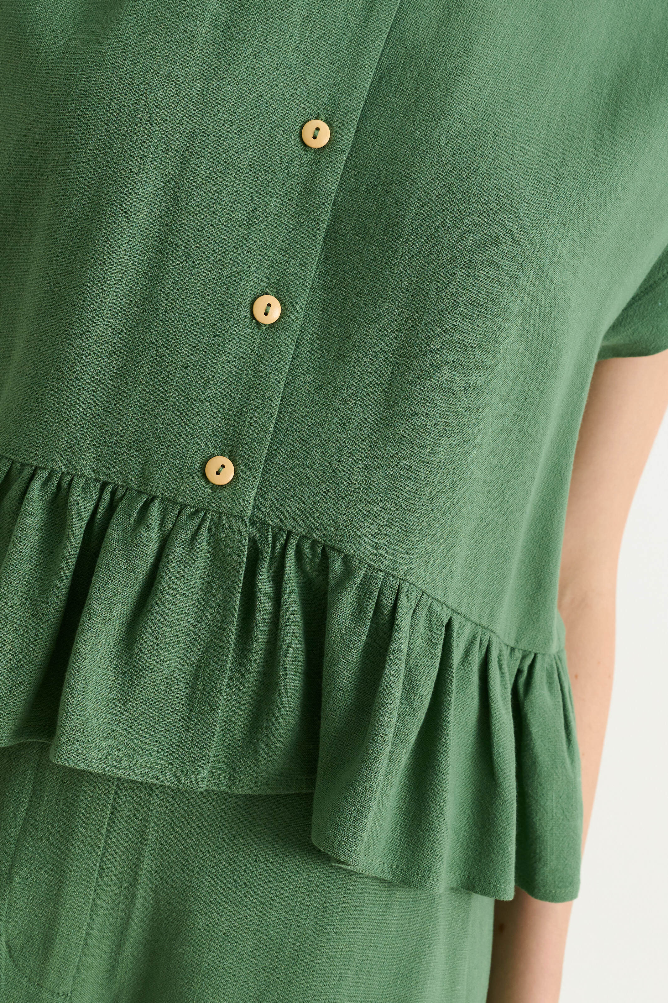 green linen-viscose blend top with extended shoulders and a frilled hem