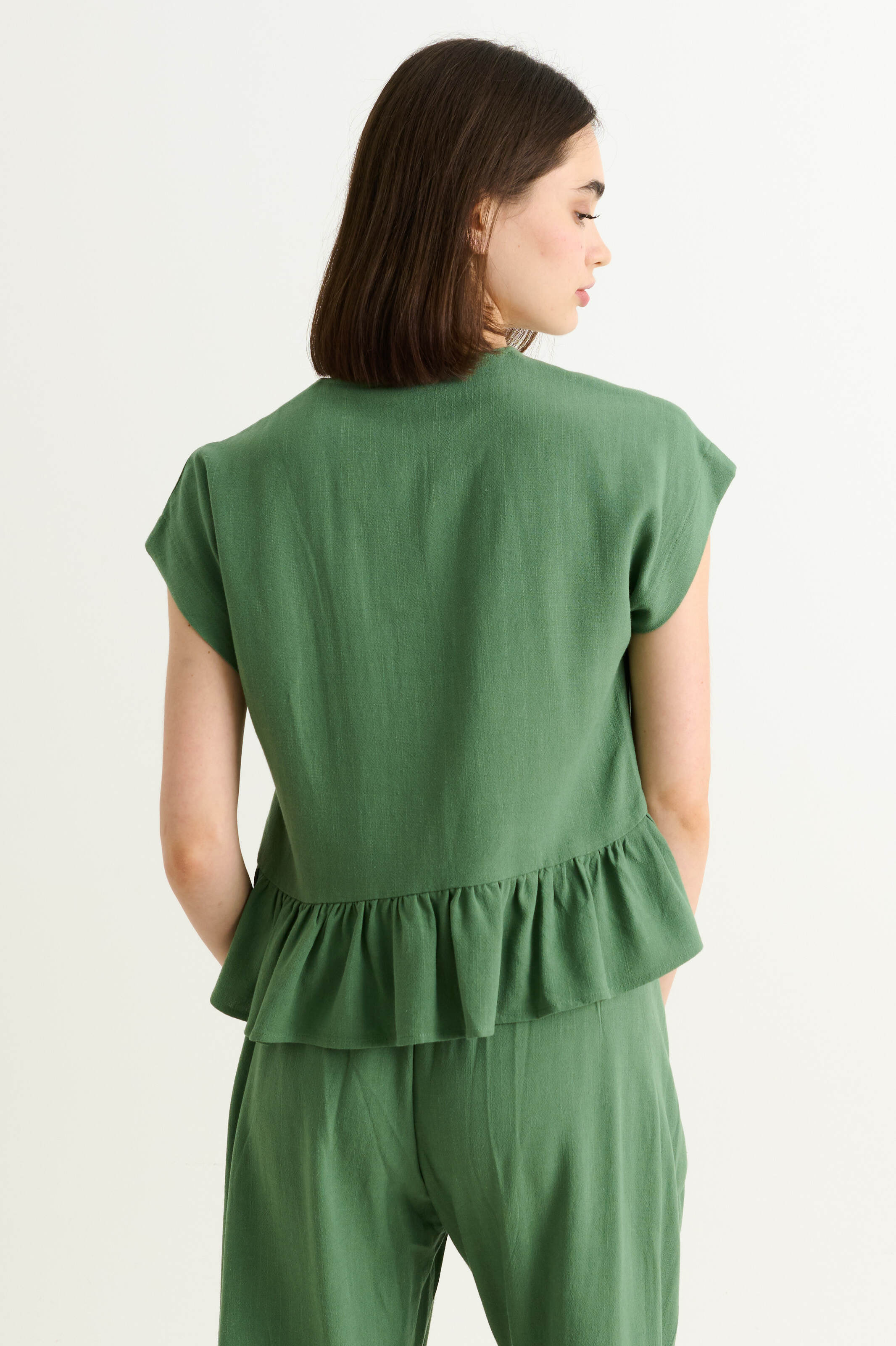 back shot of green linen-viscose blend top with extended shoulders and a frilled hem