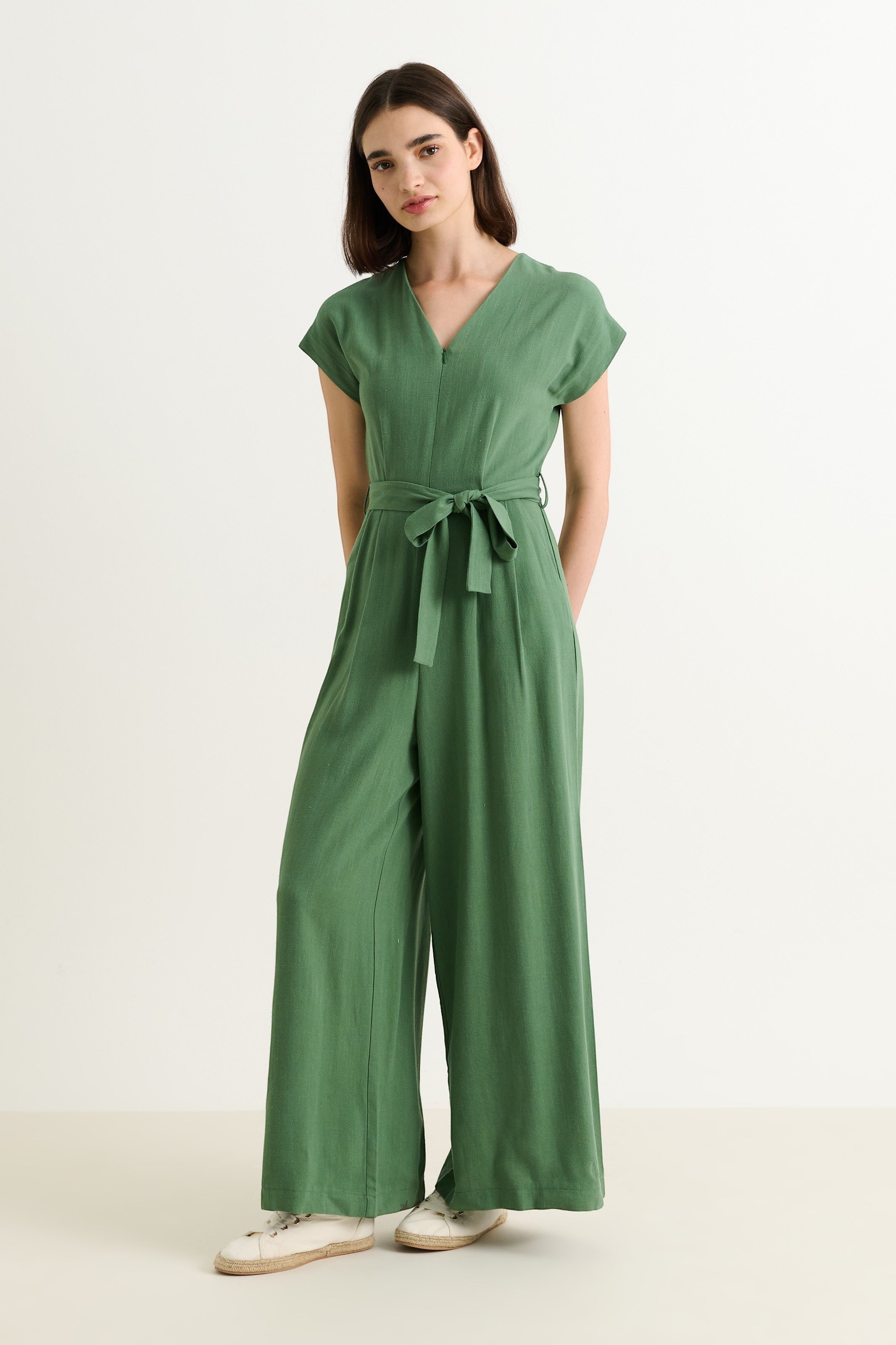 JOY green linen mix jumpsuit with V-neck, extended shoulders, self belt, and wide legs. Model is 5'8" and wearing a UK size 8.