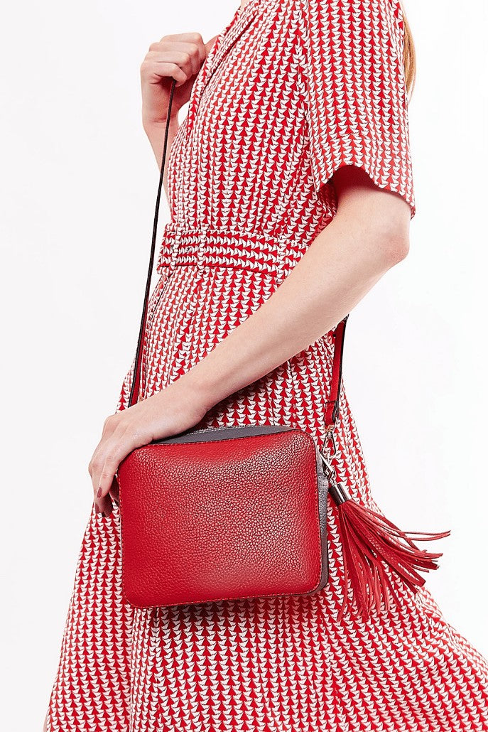 Louche Daisy red camera bag styled — bold contrast crossbody worn for a colourful summer accent.