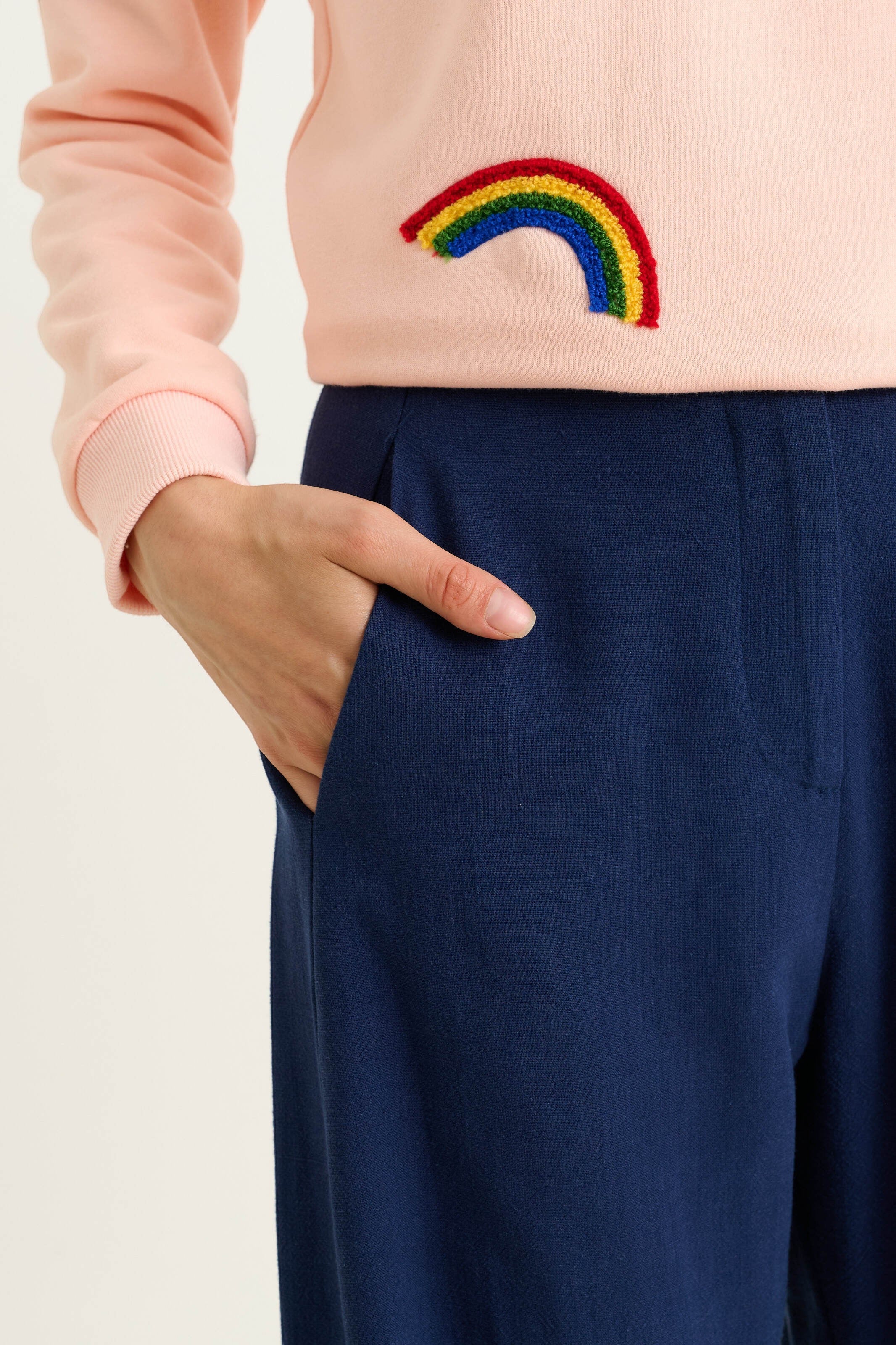 navy linen mix barrel trousers with pockets, elasticated back waist. Model wearing them with a pink sweatshirt.