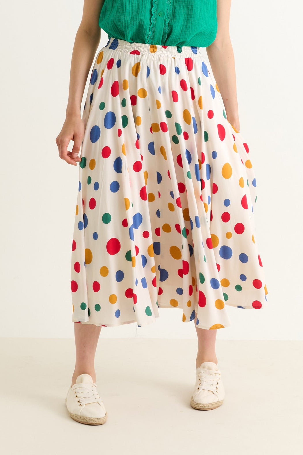Person wearing a colorful polka dot skirt on a plain background