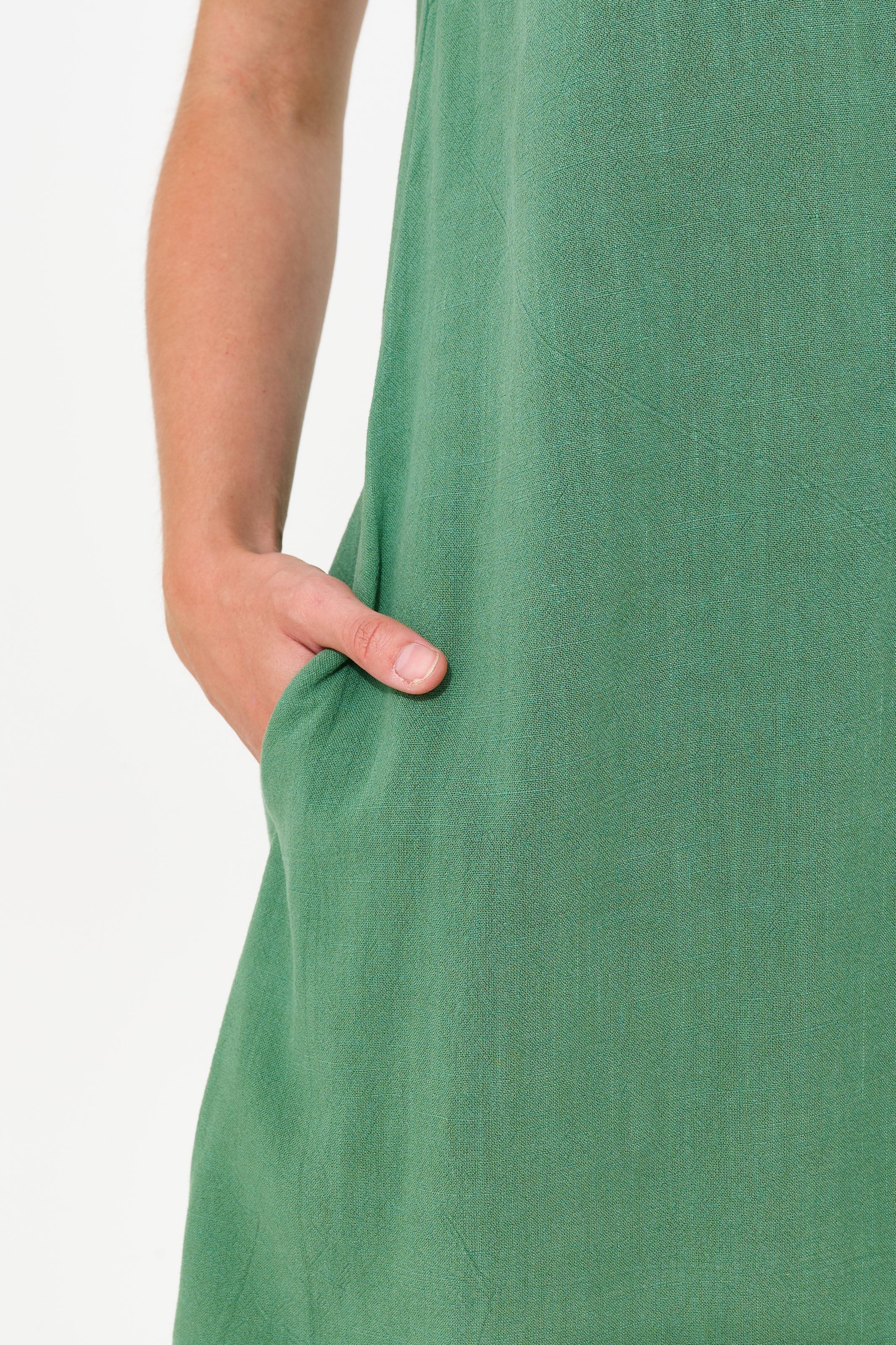 Close-up of a person wearing a sage green linen dress, showing the side pocket and hand.