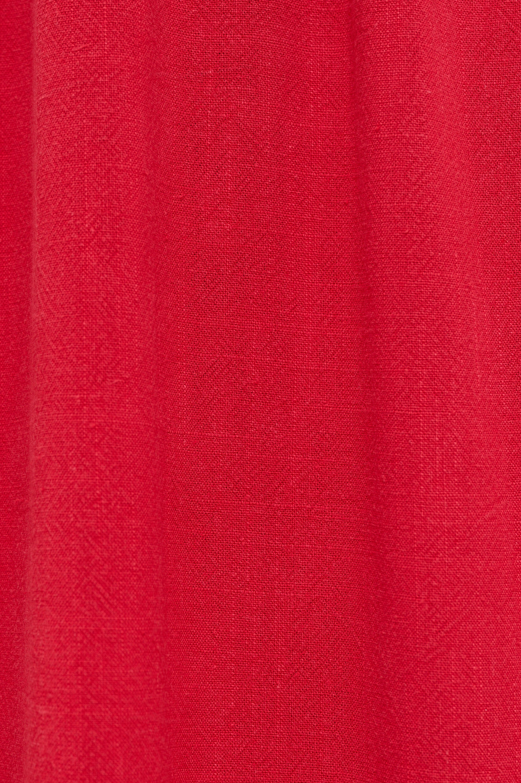 A close-up of a vibrant red textured fabric, showing a fine woven pattern and soft vertical folds.