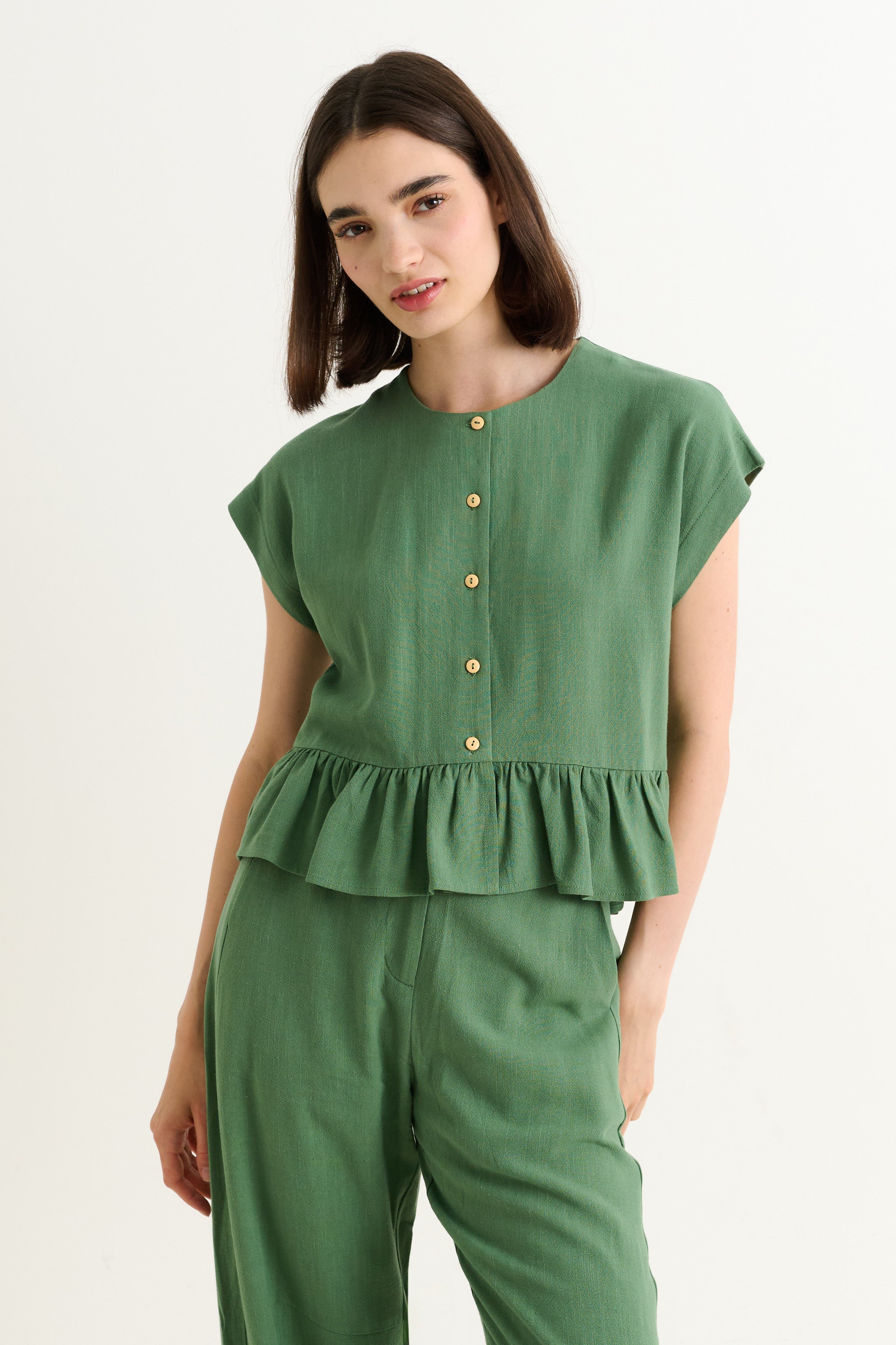 green linen-viscose blend top with extended shoulders and a frilled hem