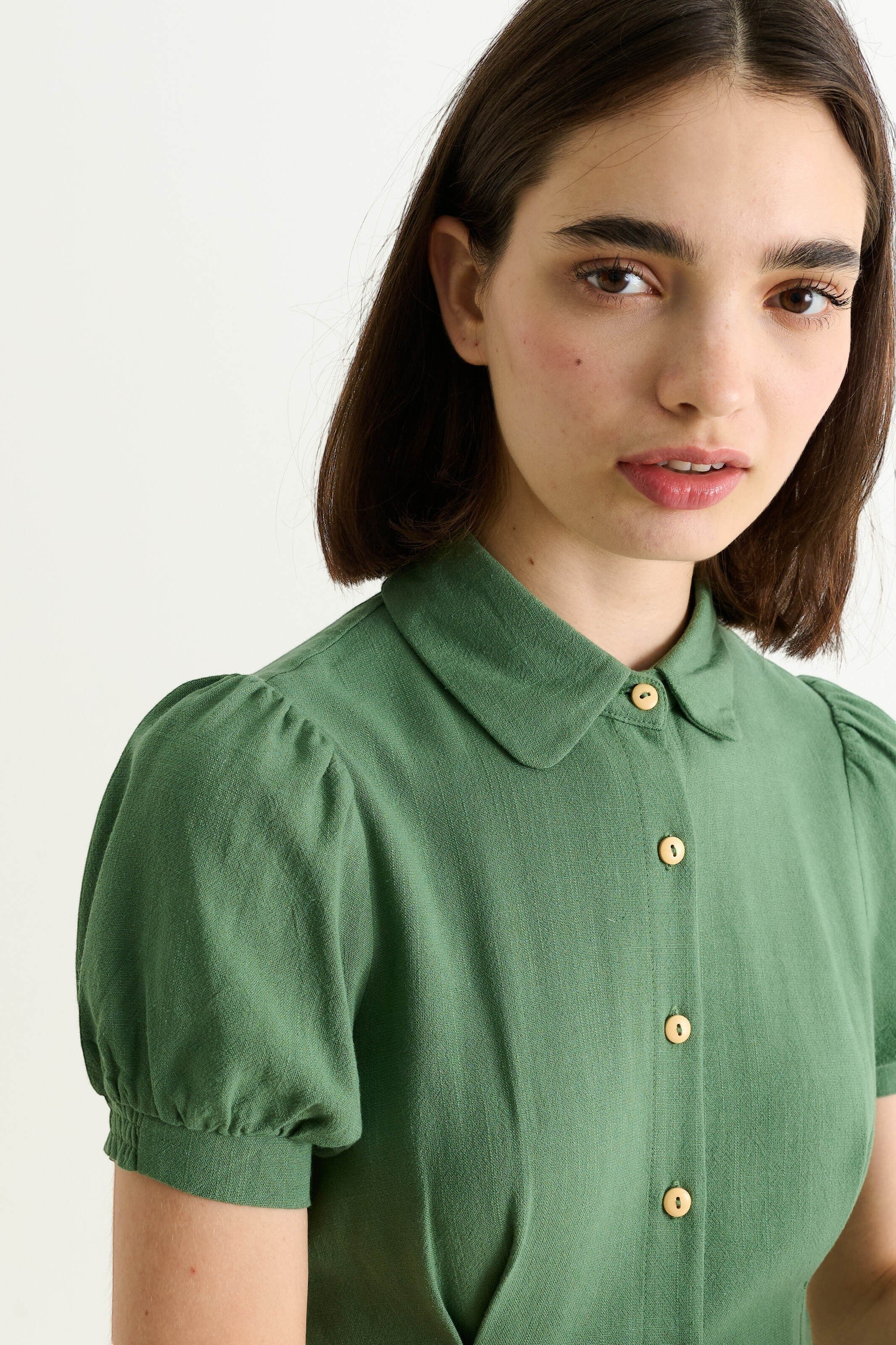 green linen mix midi shirt dress with puff sleeves, rounded collar, and wooden buttons. Model wears size 8.