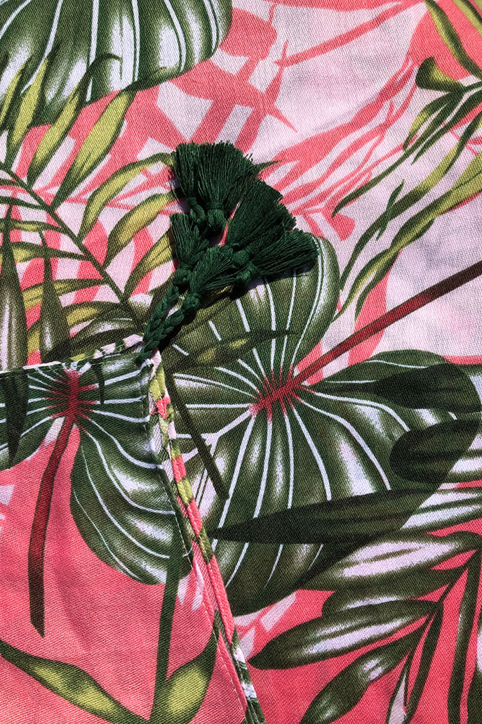 Louche Barkley banana leaf print scarf styled — tropical pink and green tassel-trim summer scarf shown worn.