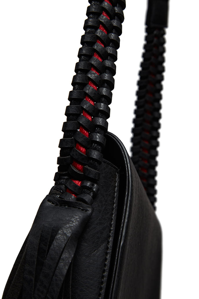 Louche Clay saddle bag detail — close-up of black PU body, plaited strap with red accent and tassel pull.